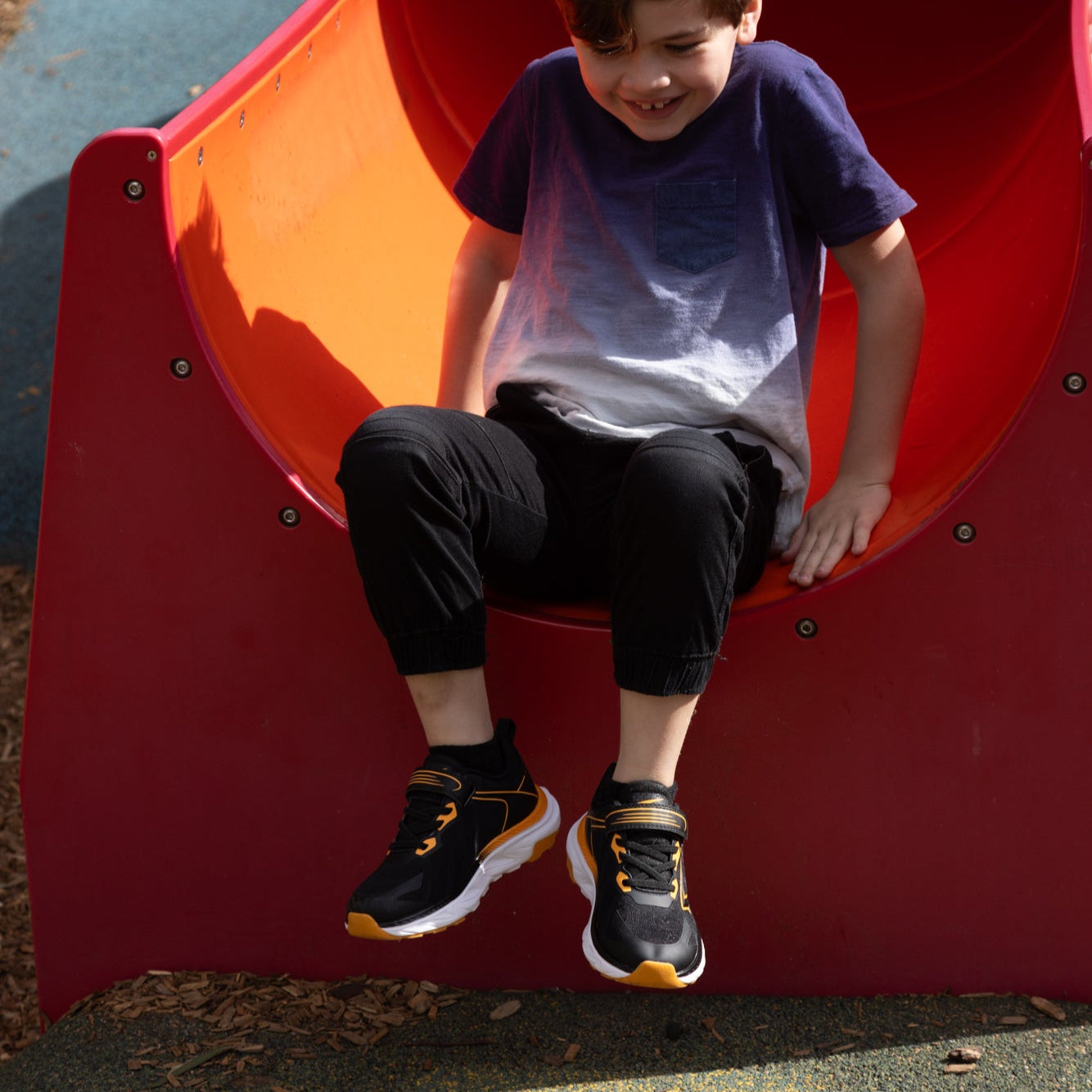 Child sitting on a red playground slide
