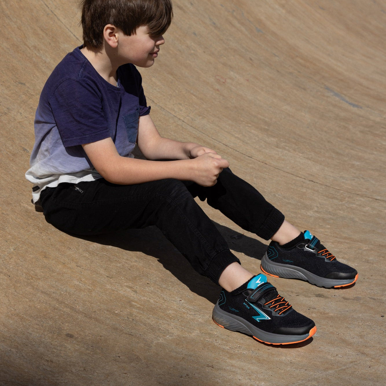 Child sitting on a wooden ramp at a skate park