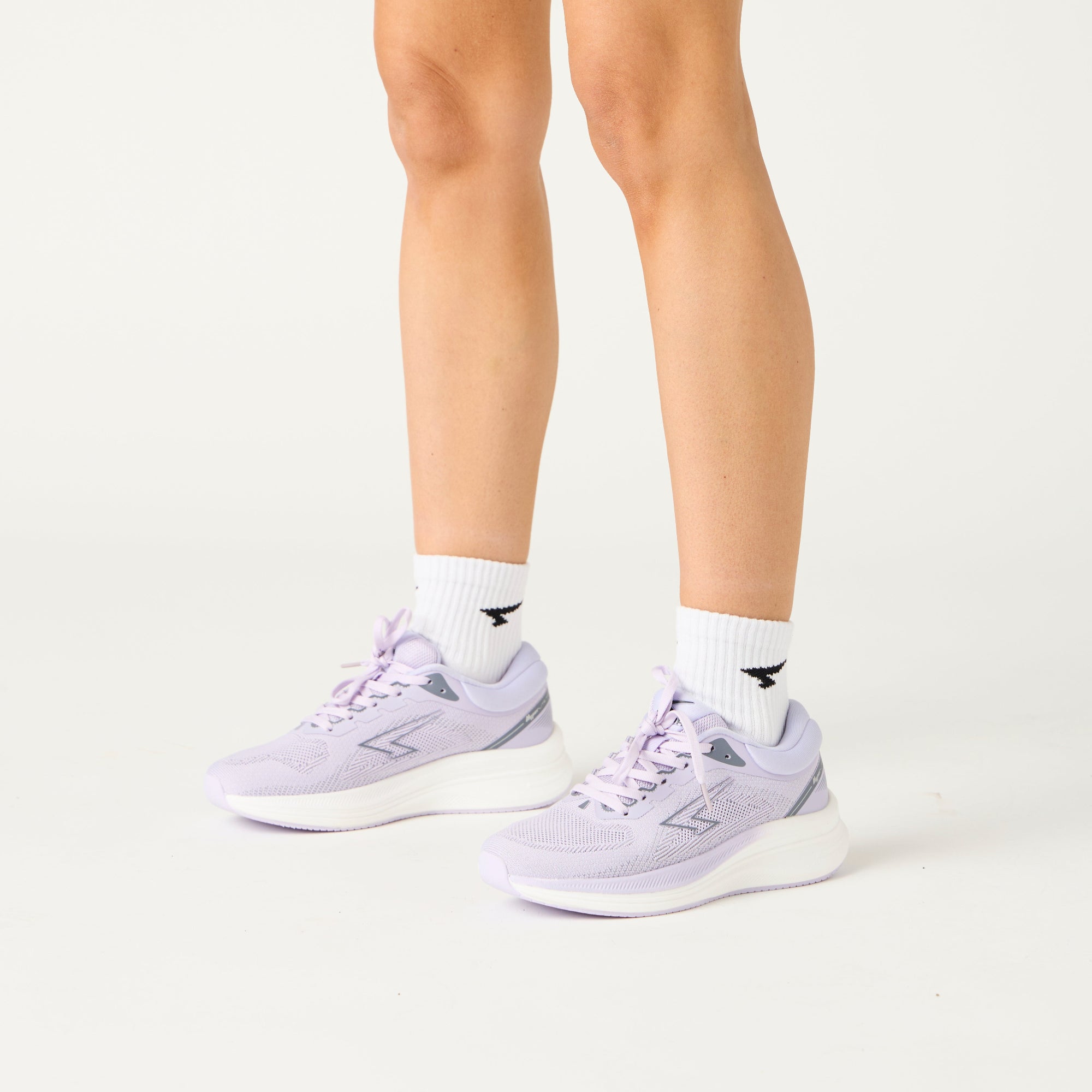 Person wearing light purple sneakers on a white background