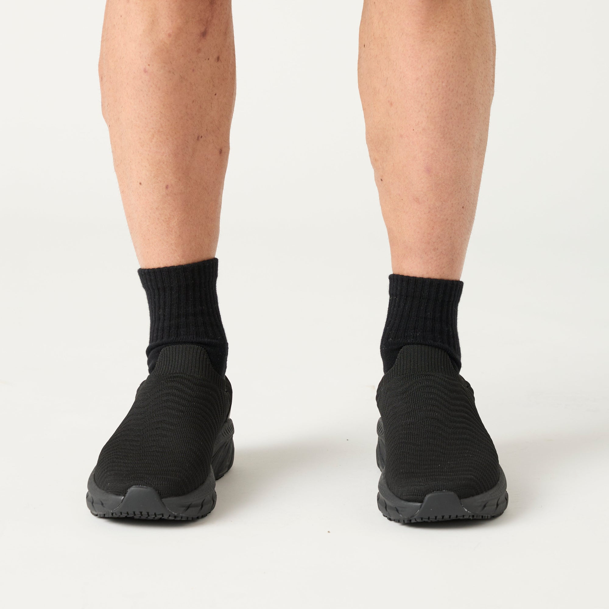 Black socks and shoes worn by a person on a white background